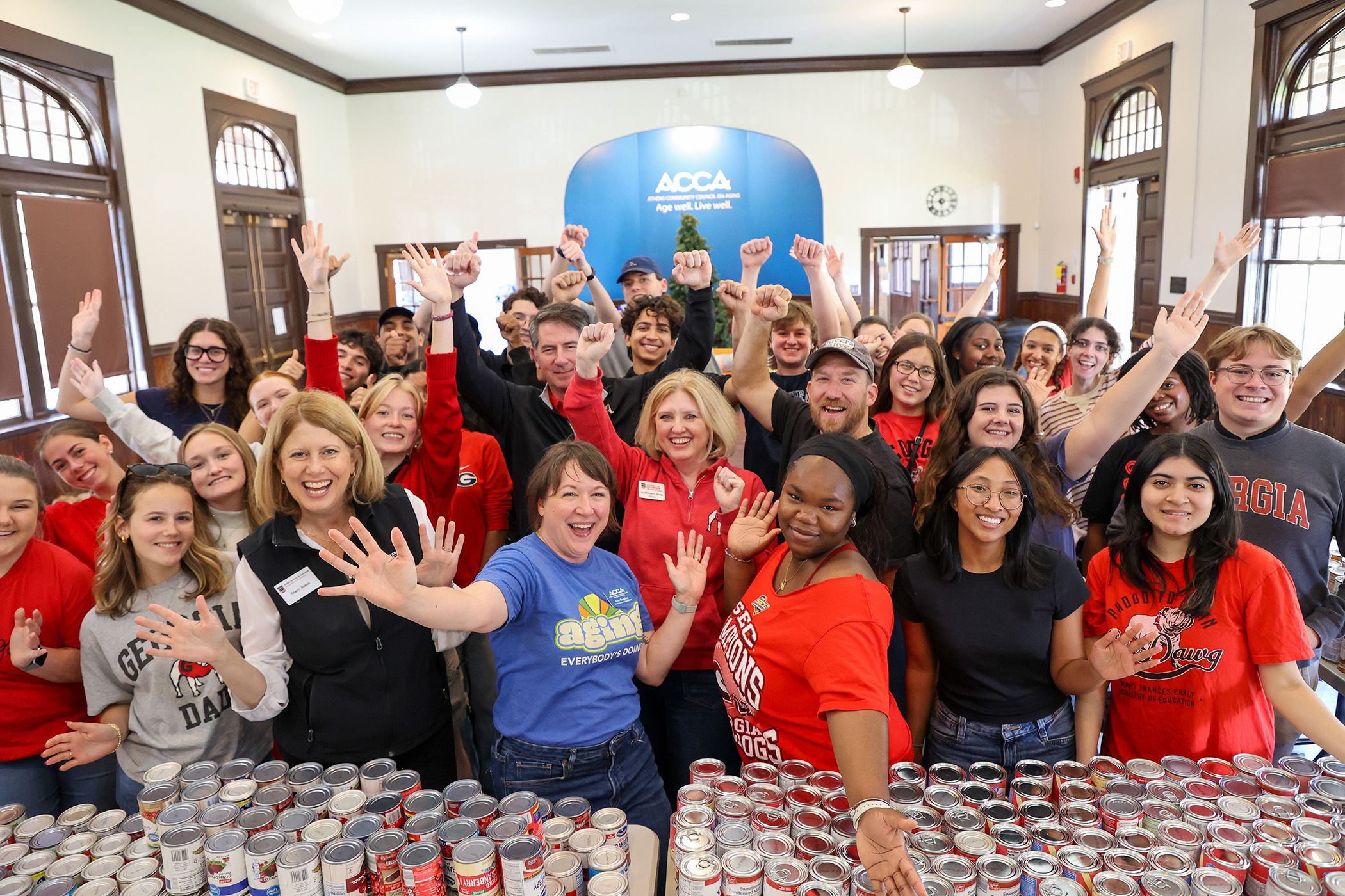 UGA students and staff take a celebratory photo with hundreds of donated food items for Turkeypalooza
