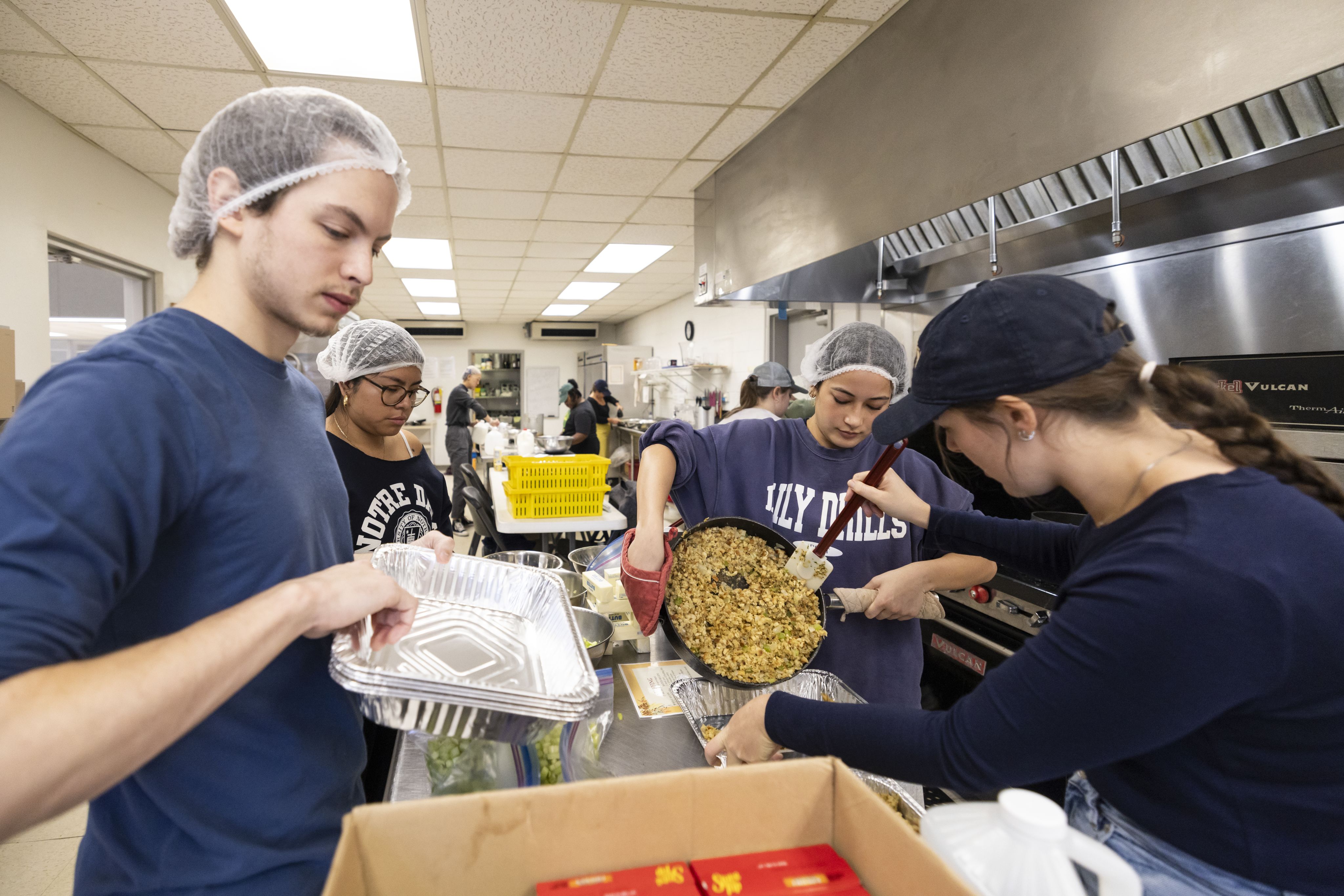 Volunteers in the kitchen prepare cooked Thanksgiving meals for Turkepalooza
