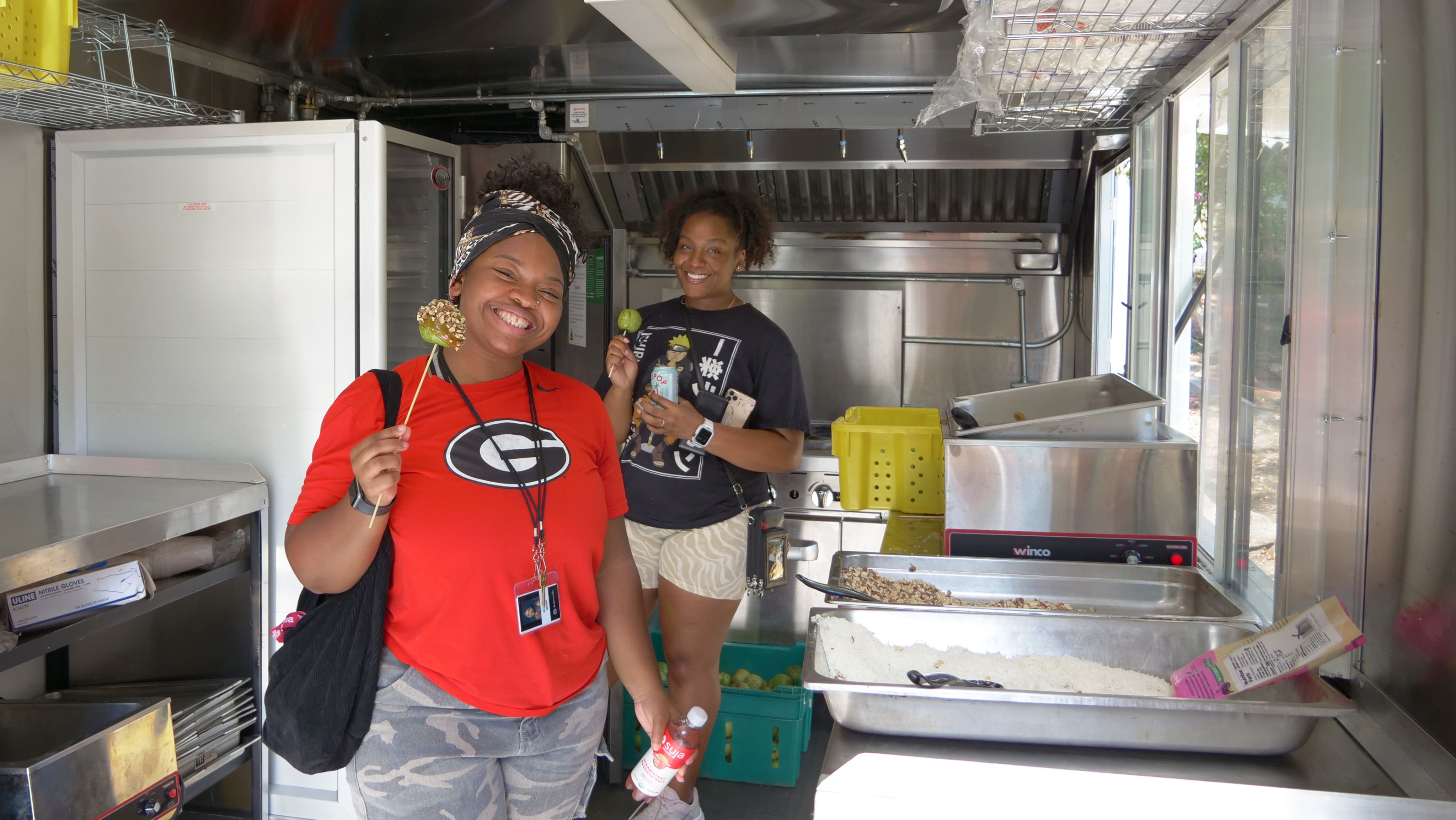 UGA students pose with caramel apples inside the Campus Kitchen trailer.