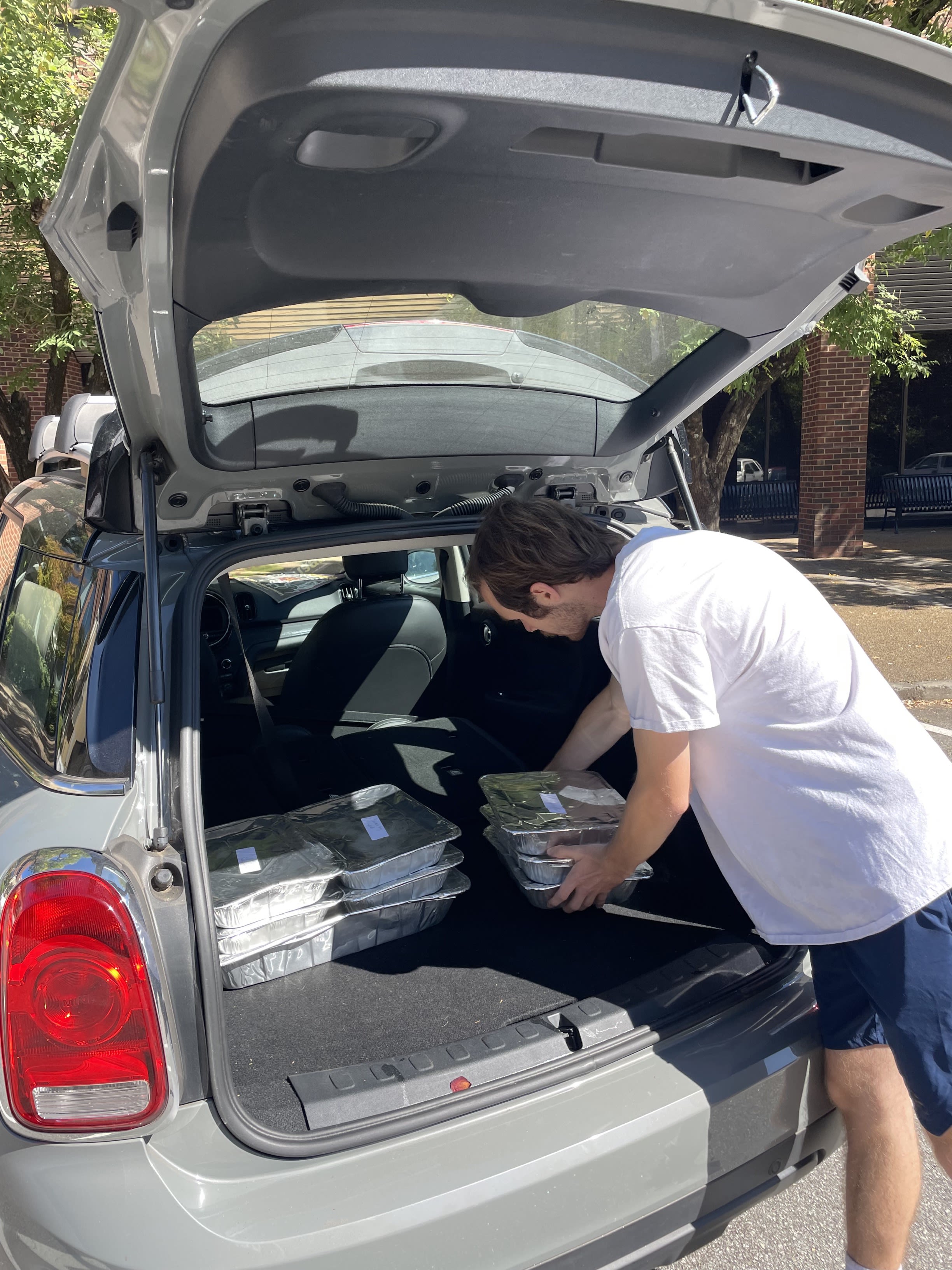A UGA student stacks containers of food from gusto! in a car.