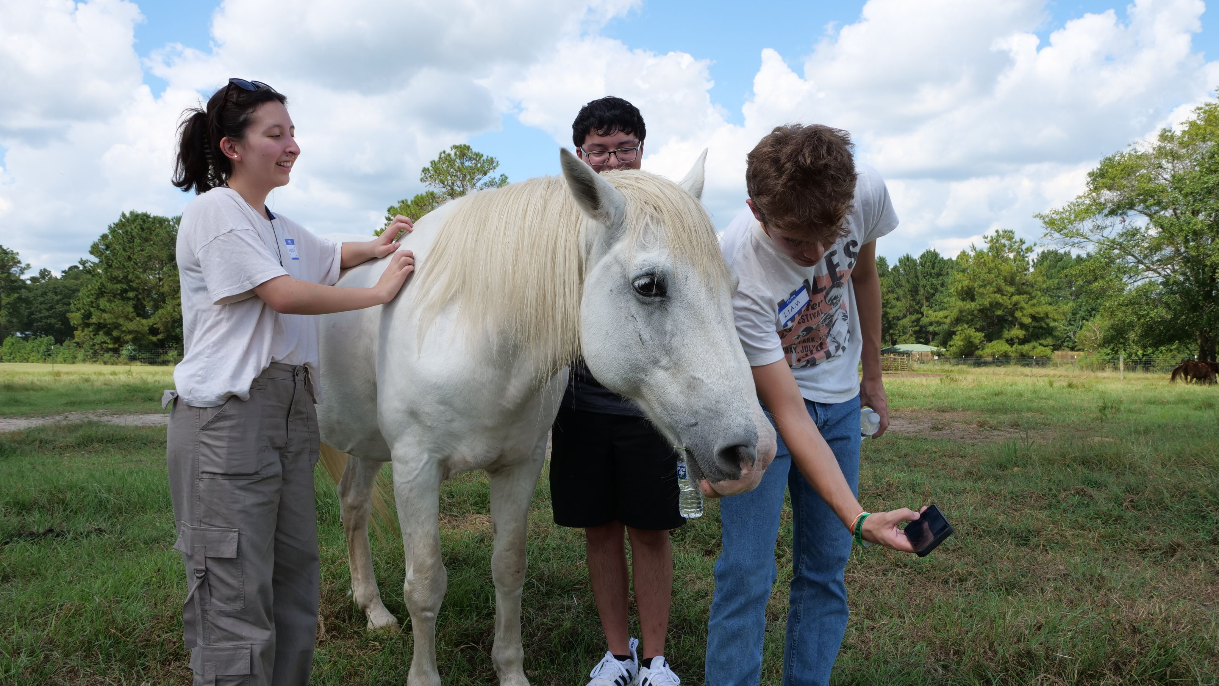 A student takes a selfie with a white mustang 