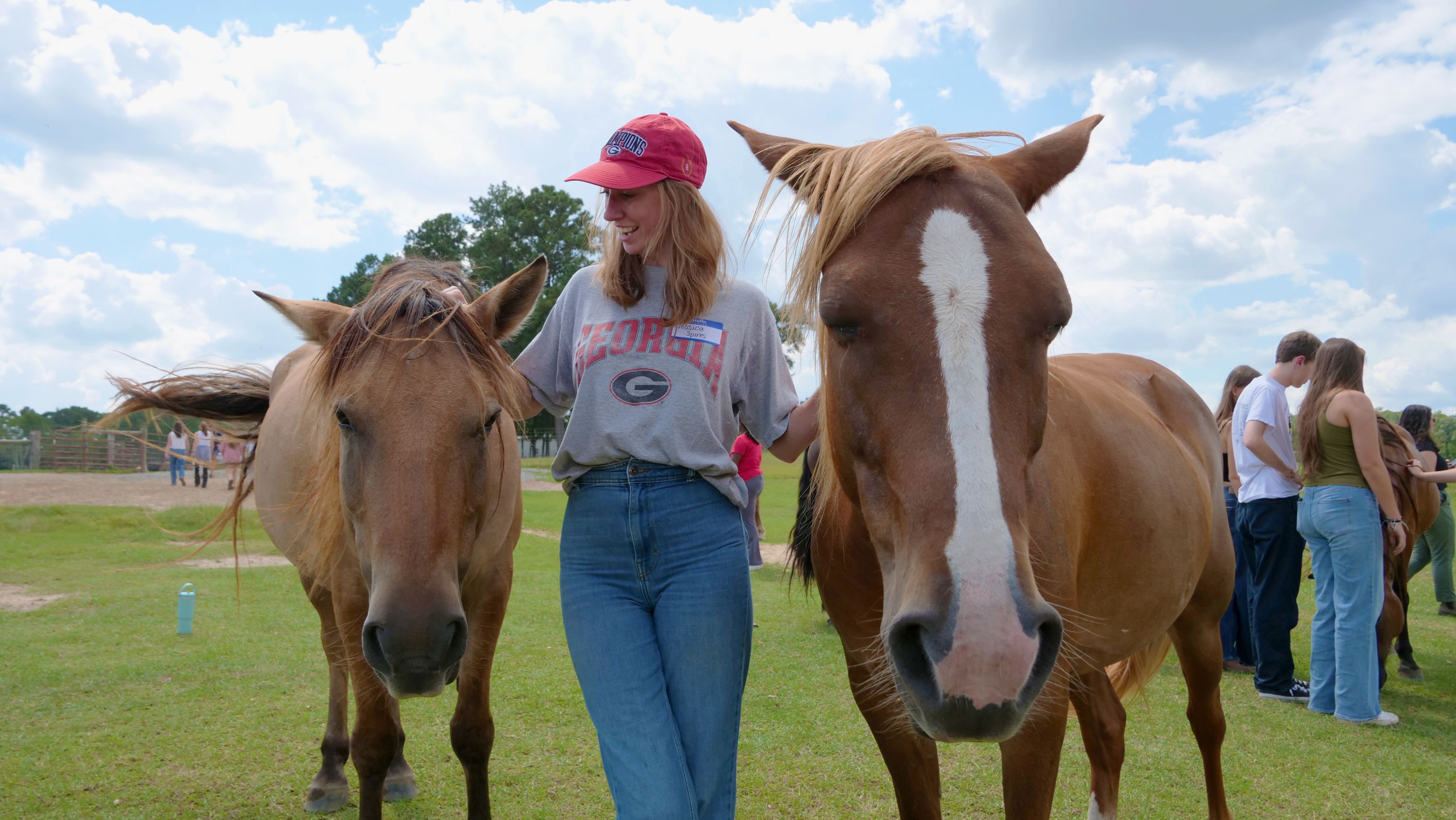 A student poses with two mustangs on either side